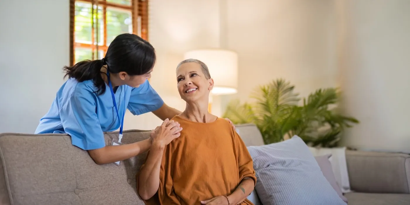 A support worker sitting with a woman on her couch at home